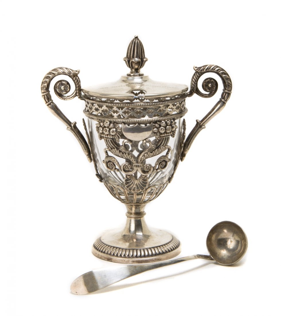 A Continental Silvered Metal and Glass Mustard Pot: A Continental Silvered Metal and Glass Mustard Pot, the hinge circular lid with acorn finial above the tapering body, set with scrolling handles, base and spoon stamped BP & 13. Height 5 1/2 inches. P
