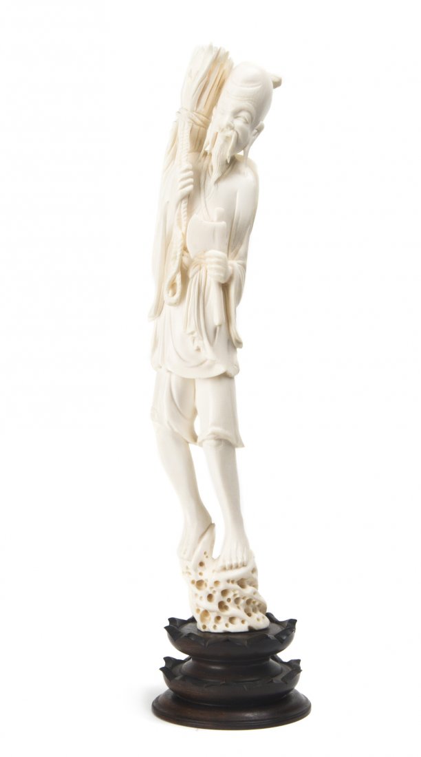 A Chinese Carved Ivory Figure, Height overall 14 1: A Chinese Carved Ivory Figure, depicting a man having a bundle on his back and holding an axe, raised on a naturalistic rockwork base, further raised on a hardwood base. Height overall 14 1/4 inches.