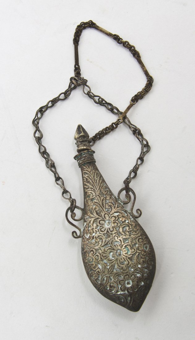 A Middle Eastern Silvered Metal Scent Flask, Heig: A Middle Eastern Silvered Metal Scent Flask, of flattened bottle form, hung with chains. Height 4 1/4 inches. Property from the Elizabeth Price Welch Legacy Collection, Chicago, Illinois