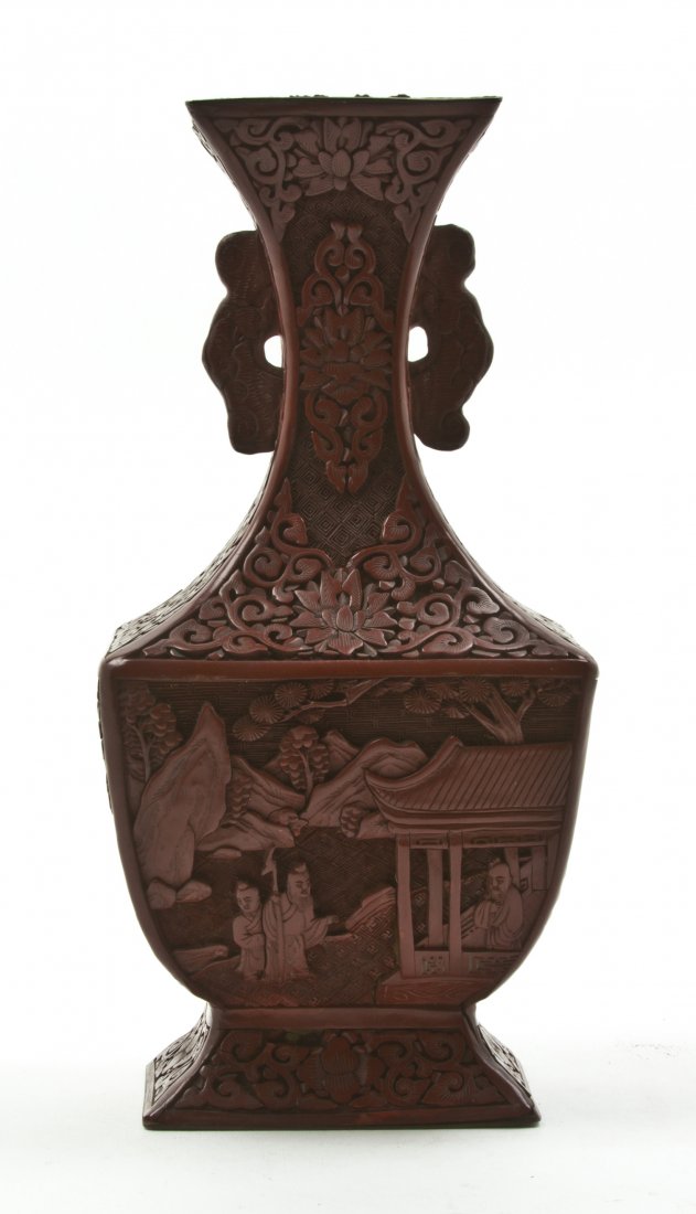 A Cinnabar Lacquered Baluster Vase, Height 10 1/8: A Cinnabar Lacquered Baluster Vase, having scrolling lotus and vine decoration and diaper pattern to the neck, flanked by bat form open handles, the body carved with figures in landscape settings with