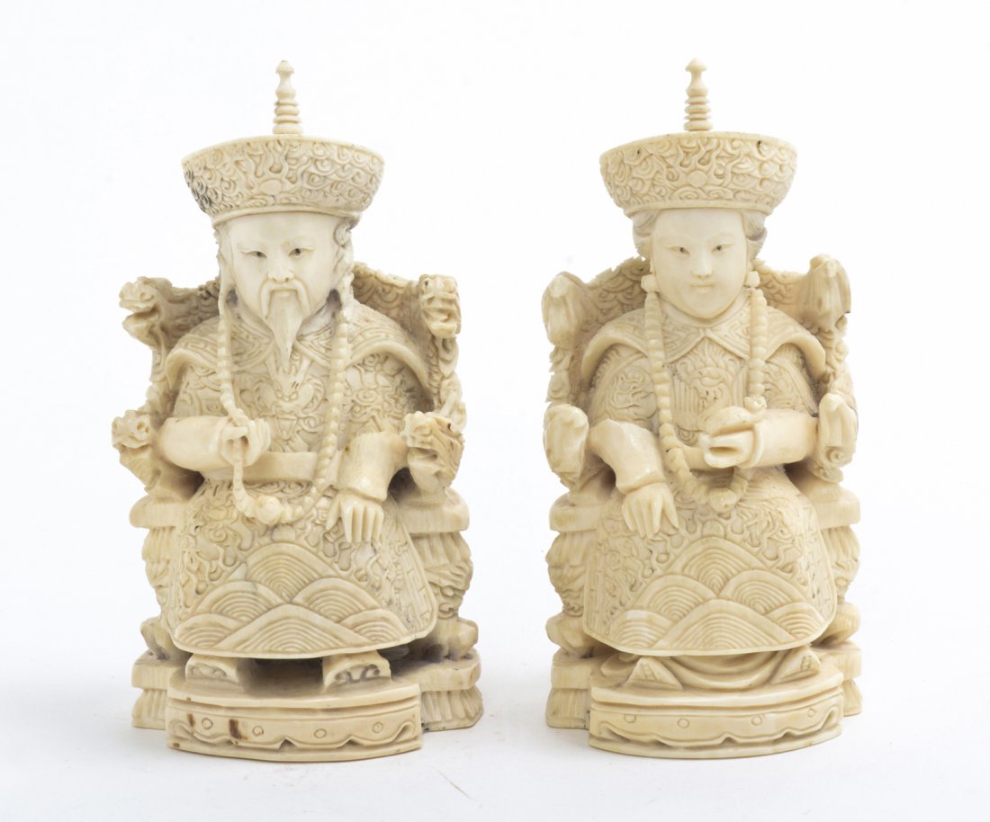 A Chinese Carved Ivory Emperor and Empress, Heigh: A Chinese Carved Ivory Emperor and Empress, each depicted crowned and seated in a throne carved with a dragon and phoenix, the man holding his beaded necklace, the woman holding a ruyi scepter. Height