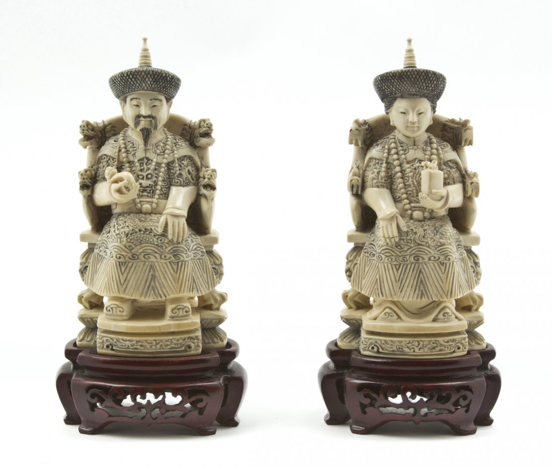A Chinese Carved Ivory Emperor and Empress, Heigh: A Chinese Carved Ivory Emperor and Empress, each depicted seated on a throne, the man holding a ruyi scepter, the lady holding a wrapped box, each throne having relief carving to the back and raised o