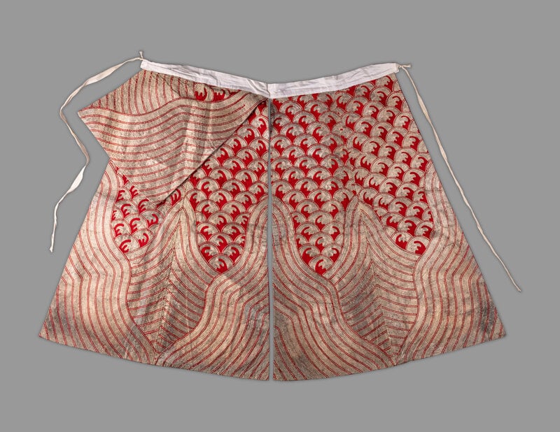 An Unusual Chinese Red and Silver Embroidered Silk Skirt: An Unusual Chinese Red and Silver Embroidered Silk Skirt 20th Century the metallic threads worked to the red ground with repeating crescents above curvilinear mountain peaks, side-tying closure.