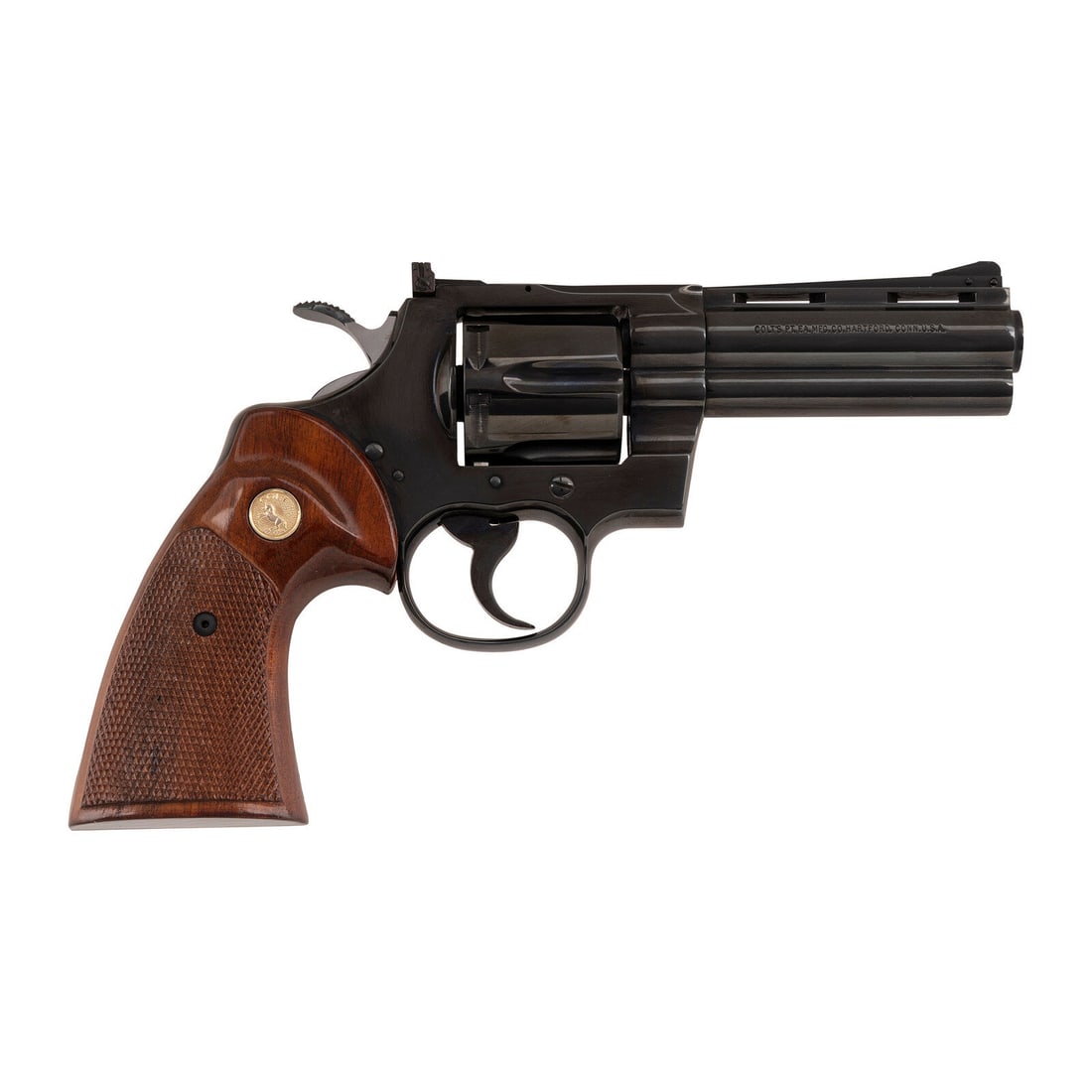 **Near Excellent Blued Colt Python Revolver with 4" Barrel: **Near Excellent Blued Colt Python Revolver with 4" Barrel .357 Magnum. 4" ventilated rib barrel. SN: E68708 (mfg. ca. 1974). Blued finish, checkered hardwood grips with gold Rampant Colt medallions. 