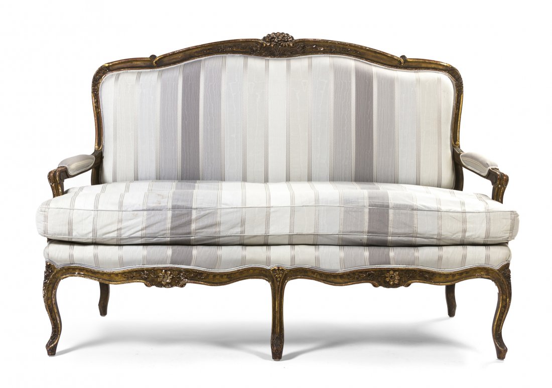 A Louis XV Style Giltwood Canape, Width 62 inches.: A Louis XV Style Giltwood Canape, having a foliate carved crest over the upholstered back, arms and seat, raised on cabriole legs. Width 62 inches. Property from the Collection of Mr. and Mrs. William