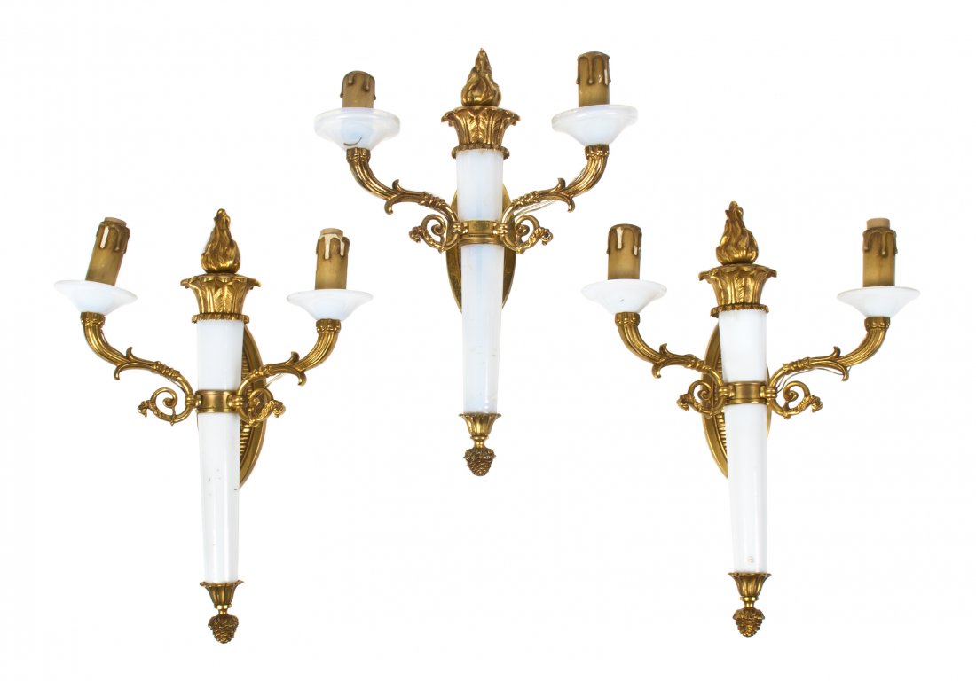 Three French Gilt Bronze and Opaline Glass Two-Lig: Three French Gilt Bronze and Opaline Glass Two-Light Sconces, each having an oval backplate supporting the torch form standard issuing the scrolling candle arms. Height 15 1/2 inches.
