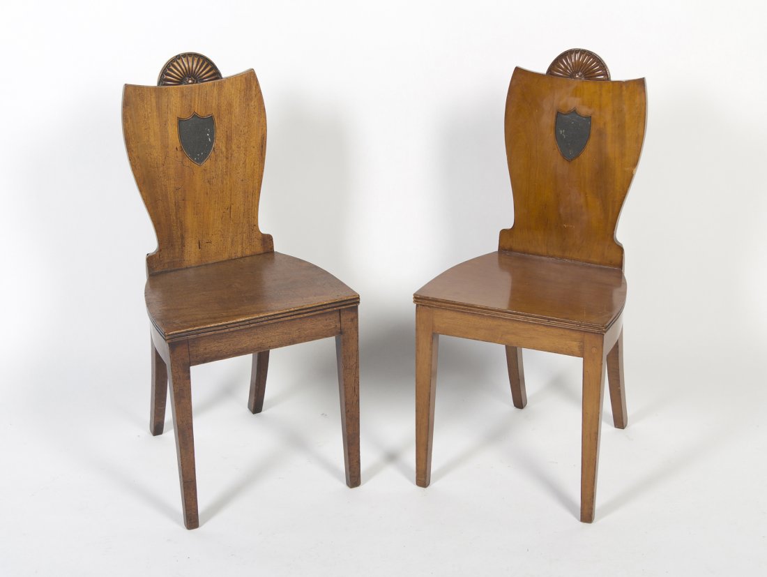 A Near Pair of Regency Hall Chairs, Height 37 inch: A Near Pair of Regency Hall Chairs, one mahogany, the other walnut, each having a shaped back carved with a fan crest over a trapezoidal plank seat, raised on tapering legs. Height 37 inches. Property