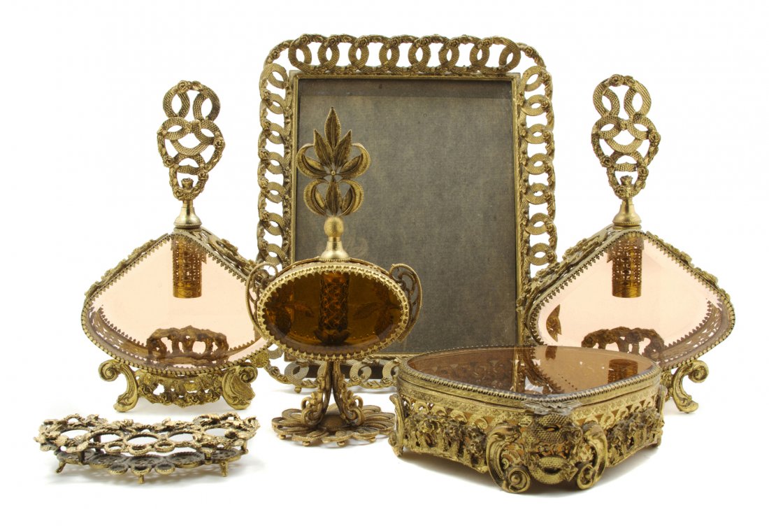 An Assembled Gilt Metal Mounted Dresser Set, Heigh: An Assembled Gilt Metal Mounted Dresser Set, comprising three scent bottles, a table casket, a picture frame, a mirrored plateau and a lipstick holder. Height of tallest 10 1/4 inches. Property from t