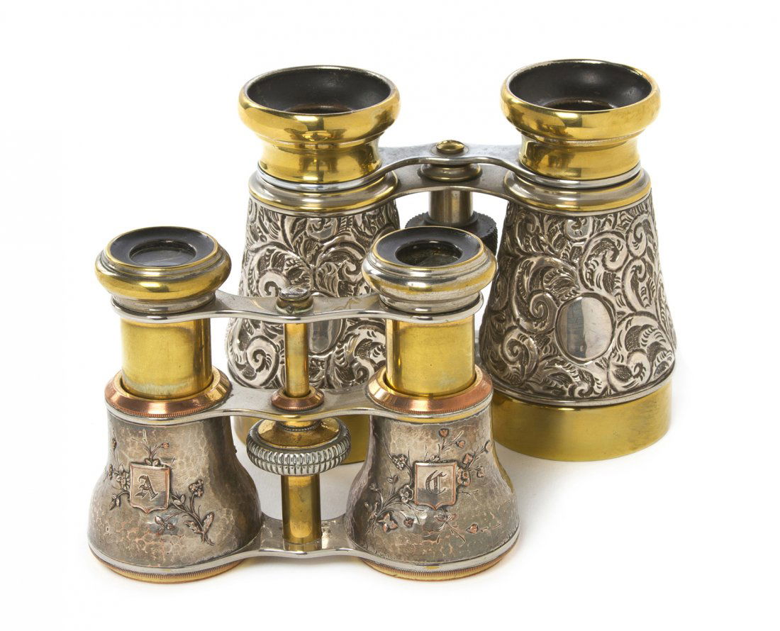 Two Pairs of Continental Silver or Silvered Metal: Two Pairs of Continental Silver or Silvered Metal Cased Opera Glasses, the first with allover scrolling foliate decoration, the second with figures amidst flowers. Width of first 4 1/2 inches. Propert