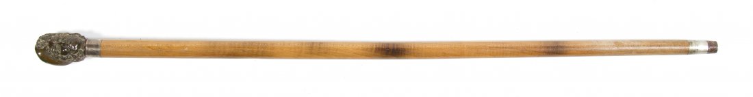 A Carved Horn and Wood Walking Stick, Height over: A Carved Horn and Wood Walking Stick, depicting a gentleman in a hat, set with a silvered collar, raised on a tapering shaft. Height overall 35 1/2 inches. Property from the Estate of Mr. Mark Fritz,