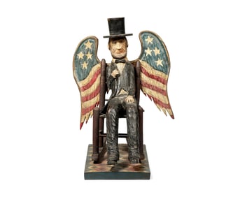 A Carved And Painted Figure Of A Seated Abraham Lincoln With Wings Painted As American Flag