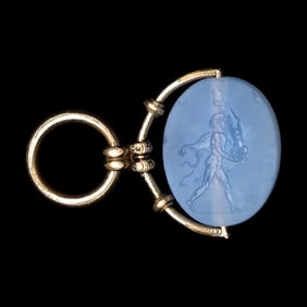 A Greek Blue Chalcedony Intaglio with a Satyr Holding a Herm