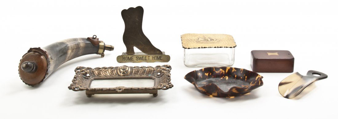 A Collection of Decorative Table Articles, Length of fi: A Collection of Decorative Table Articles, comprising a powder horn, a bronze and stone inset dish, a shoe horn, a brass lidded box, a tortoise shell bowl, a brass shoe and a mahogany box. Length of f