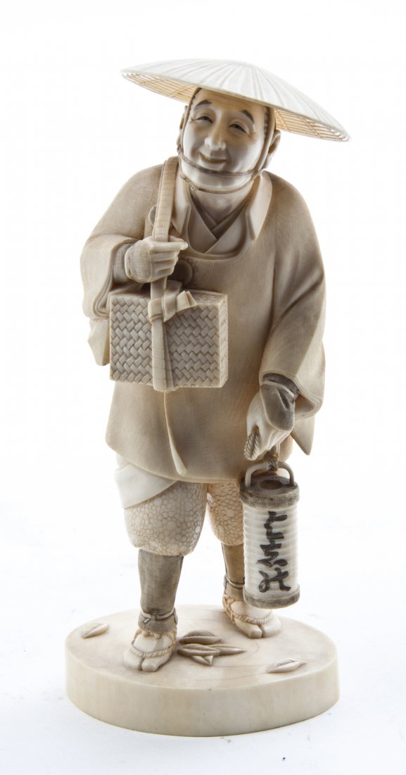 A Japanese Carved Ivory Figure, Height of figure 7 1/2 : A Japanese Carved Ivory Figure, depicting a man wearing a hat and holding a lantern, raised on a shaped circular base, signed with red character marks to underside of base. Height of figure 7 1/2 inch