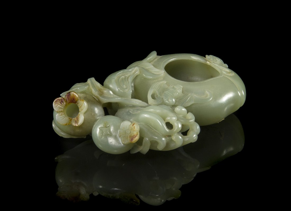 A Carved Jade Coupe, Width 4 5/8 inches.: A Carved Jade Coupe, of a celadon colored stone having russet inclusions, the circular coupe having bats carved around the mouth rim, with a Buddha's hand citron and leafy fruits and gourds carved to 