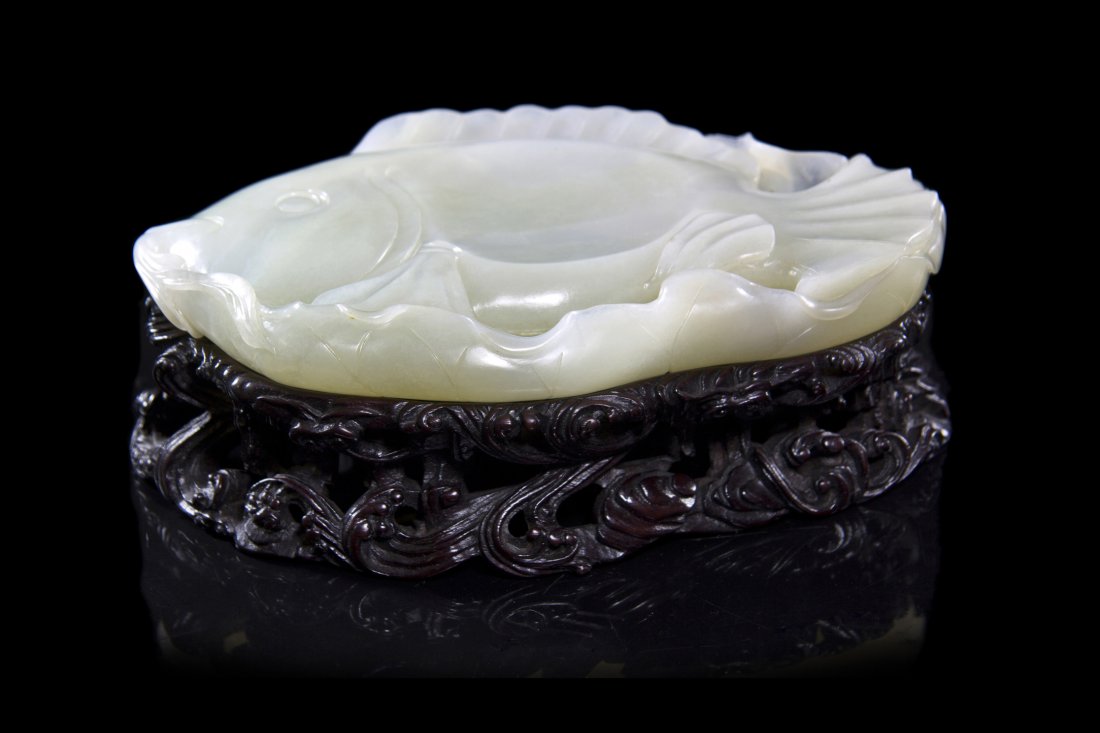 A Carved White Jade Fish-Form Inkstone, Width at widest: A Carved White Jade Fish-Form Inkstone, of an even, white stone, the fish depicted in profile and resting on a curling leaf with its fins carved in deep grooves, centered by a circular well, the under