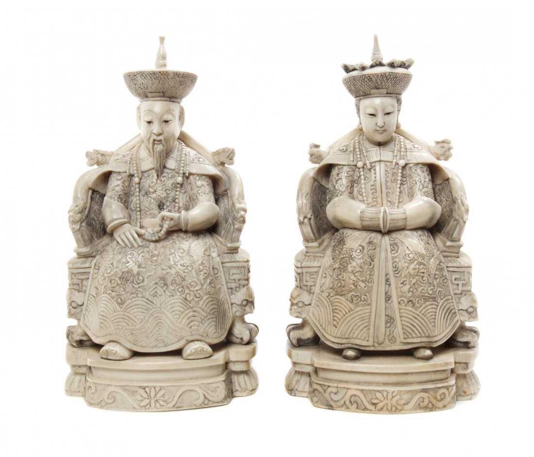 Two Chinese Carved Ivory Emperor and Empress Figures, H: Two Chinese Carved Ivory Emperor and Empress Figures, each depicted seated in a dragon or phoenix carved throne, the man holding his beaded necklace in one hand, the lady with her hands clasped togeth