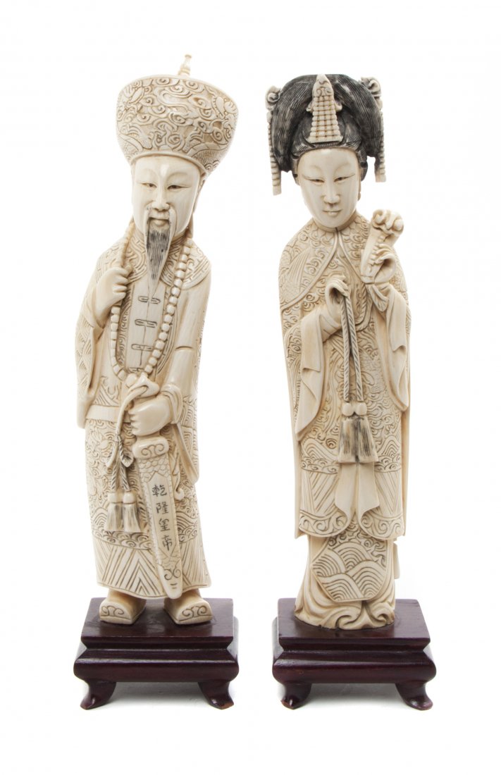 A Pair of Chinese Carved Ivory Figures of an Emperor an: A Pair of Chinese Carved Ivory Figures of an Emperor and Empress, each depicted standing with elaborate headdress, the man holding his beaded court necklace, the lady with a ruyi scepter, raised on ha
