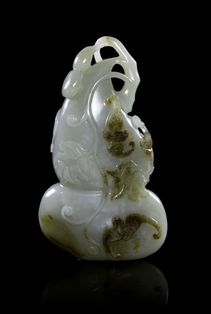 A Carved Jade Double Gourd-Form Toggle, Height 5 1/4 in: A Carved Jade Double Gourd-Form Toggle, of a celadon colored stone having russet skin and inclusions, depicted with smaller gourd-form fruits, scrolling vines, leafy tendrils, and bats. Height 5 1/4 i