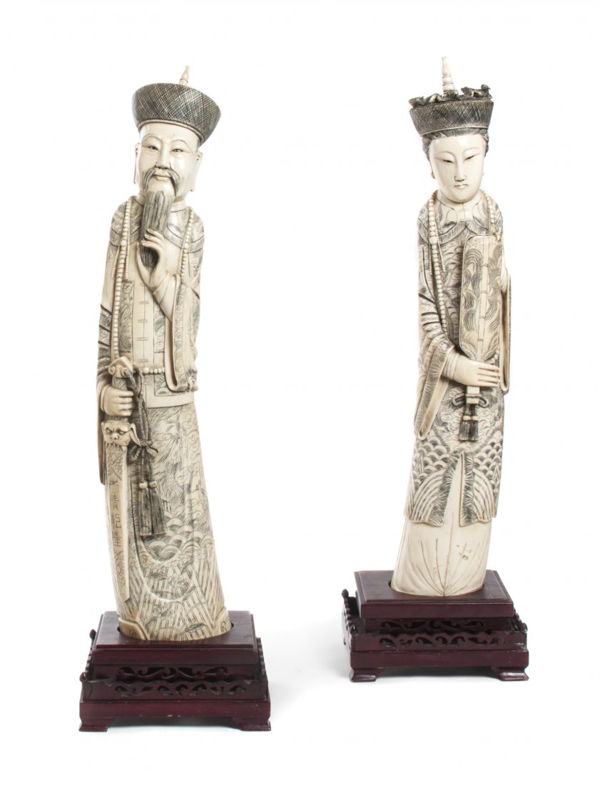 A Chinese Carved Ivory Emperor and Empress, Height of t: A Chinese Carved Ivory Emperor and Empress, each depicted standing in court robes and court necklaces, the man with a hand on his beard and the other hand grasping his sword, the lady holding a fan, e