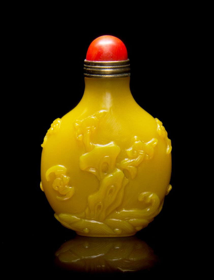 A Yellow Peking Glass Snuff Bottle, Height 2 1/8 inches: A Yellow Peking Glass Snuff Bottle, of a compressed flask form with raised double handles and decoration depicting bats flying amongst lingzhi fungi emerging from rocks, with a domed coral stopper. He