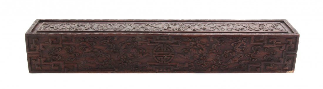 A Chinese Hardwood Scroll Box, Height 3 1/4 x width 19 : A Chinese Hardwood Scroll Box, of rectangular form, the relief carved decoration depicting bats and scrolling clouds with geometric designs and centered with a shou medallion. Height 3 1/4 x width 19 