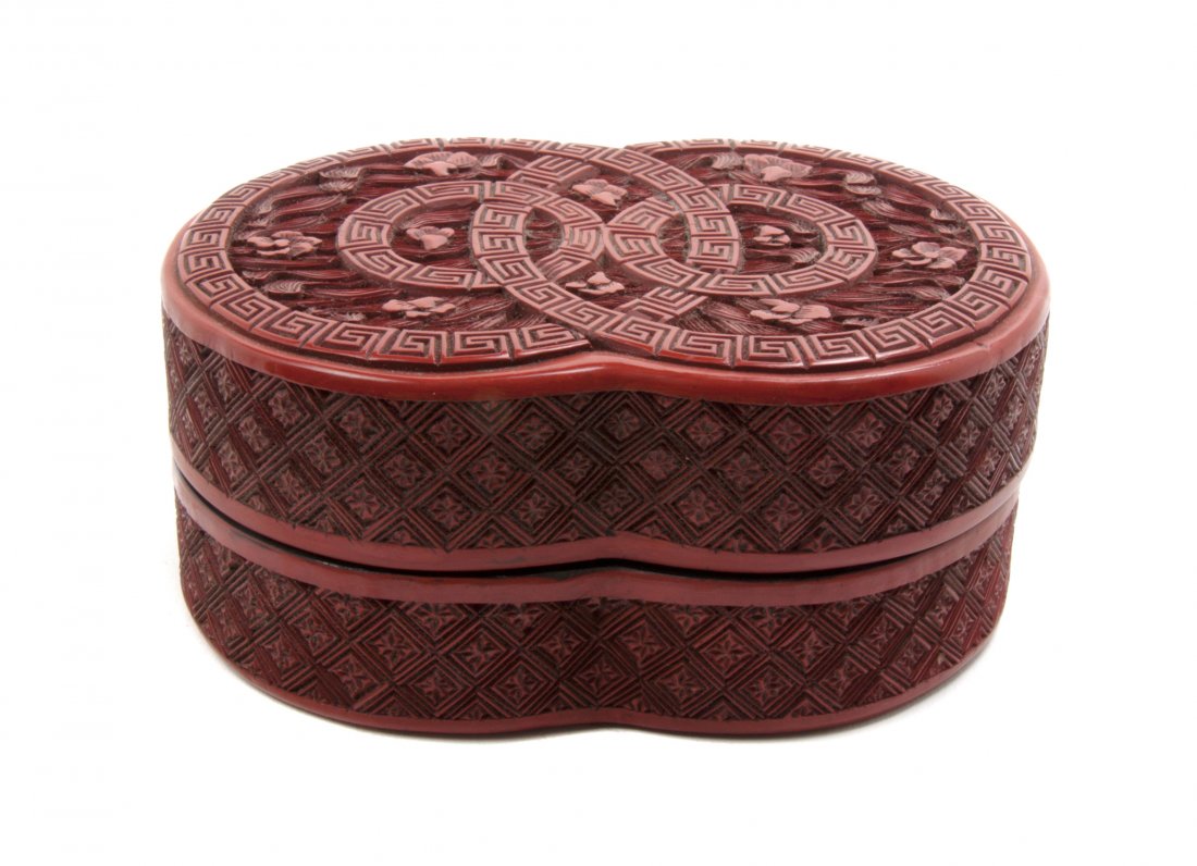A Chinese Cinnabar Lacquered Double Coin-Form Lidded Bo: A Chinese Cinnabar Lacquered Double Coin-Form Lidded Box, having relief carved decoration throughout and with diaper pattern to the sides, bearing a Qianlong mark to the underside. Length 4 3/4 inches