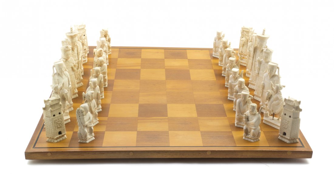 A Chinese Carved Ivory Chess Set, Height of tallest pie: A Chinese Carved Ivory Chess Set, comprising thirty-two pieces and a wood game board. Height of tallest piece 6 1/4 inches.