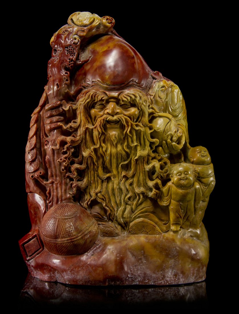 A Chinese Carved Steatite Figure of Shoulao, Height 17 : A Chinese Carved Steatite Figure of Shoulao, the immortal depicted with a gnarled staff and peach, with a fibrous, root-like beard, with two figures of young boys and a ball. Height 17 3/8 inches.