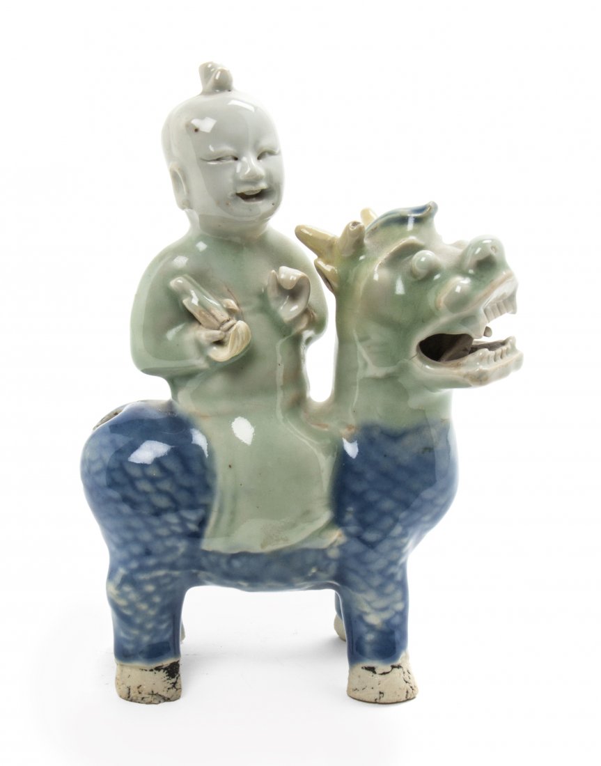 A Chinese Porcelain Figural Water Dropper, Height 7 3/8: A Chinese Porcelain Figural Water Dropper, of celadon and underglaze blue color, in the form of a child riding a qilin. Height 7 3/8 inches. Property from the Collection of Dr. Stuart Weiss and Mrs. M