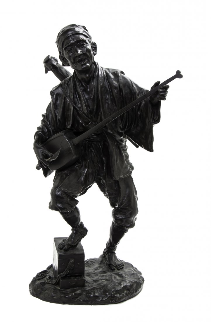 A Japanese Bronze Figure of a Musician, Height 23 1/4 i: A Japanese Bronze Figure of a Musician, Meiji Period, the elderly shamisen player cast with a jovial expression, wearing rope sandals with one foot raised upon a chest, set on a naturalistic base. Hei