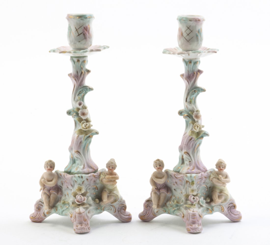 A Pair of German Porcelain Candlesticks, Height 8 3/4 i: A Pair of German Porcelain Candlesticks, each having a naturalistically modeled standard over the figural and flower decorated bases, having crossed double line mark in underglazed blue. Height 8 3/4