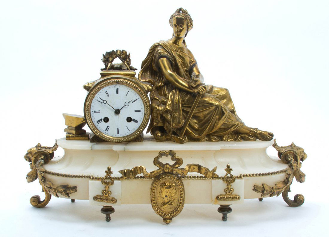 A Continental Gilt Metal and Alabaster Mantel Clock, Wi: A Continental Gilt Metal and Alabaster Mantel Clock, having a maiden allegorical of industry next to the circular enameled dial with Roman hours, raised on the shaped oval base centered with a ribbon-