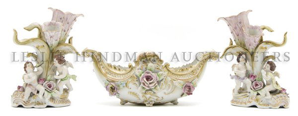 A Japanese Porcelain Three Piece Garniture Set, Argalt,: A Japanese Porcelain Three Piece Garniture Set, Argalt, in the European taste, having a floral decorated oval center bowl suspended between two figural supports. Width overall 24 inches.