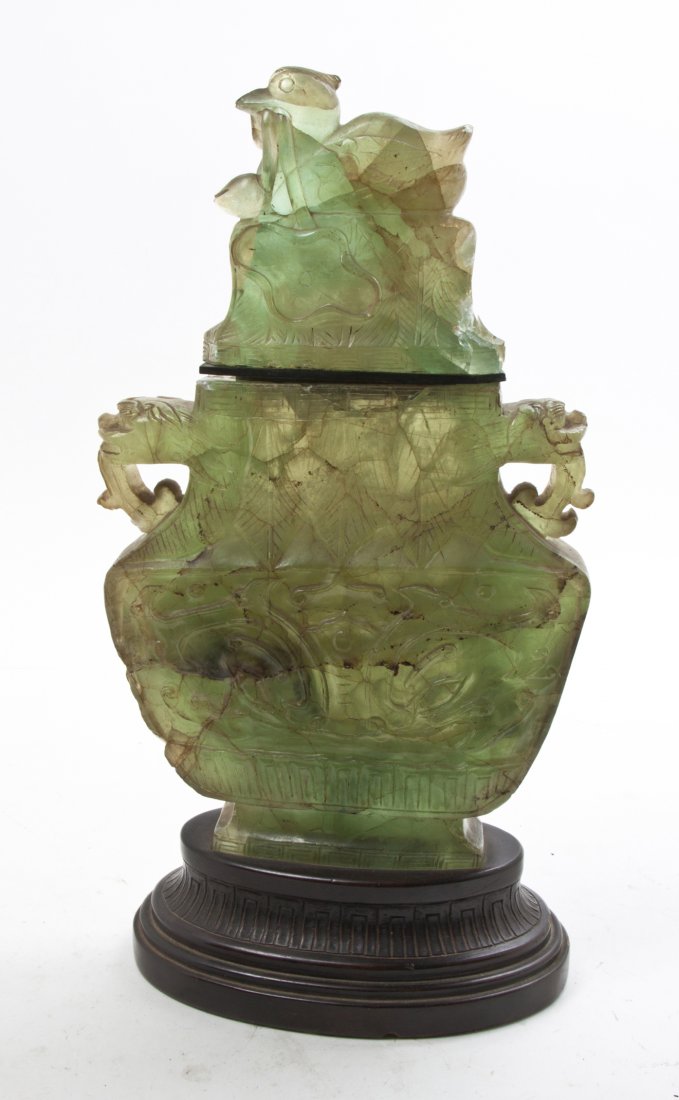 A Chinese Hardstone Lidded Vase, Height 17 1/4 x width : A Chinese Hardstone Lidded Vase, having a finial in the form of a duck clutching the stem of a lotus pad in its beak, the body flanked by animal mask handles and having carving in relief to the main c