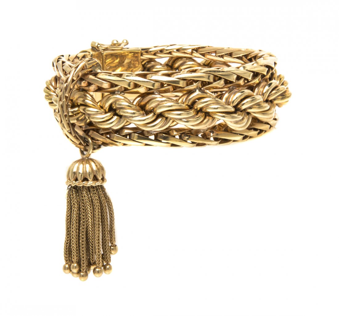 A 14 Karat Yellow Gold Bracelet, 42.90 dwts.: A 14 Karat Yellow Gold Bracelet, consisting of a central section of rope chain with sides of woven chain and a tassel accent. Stamp: 14K. Length: 6 1/2 inches. 42.90 dwts.