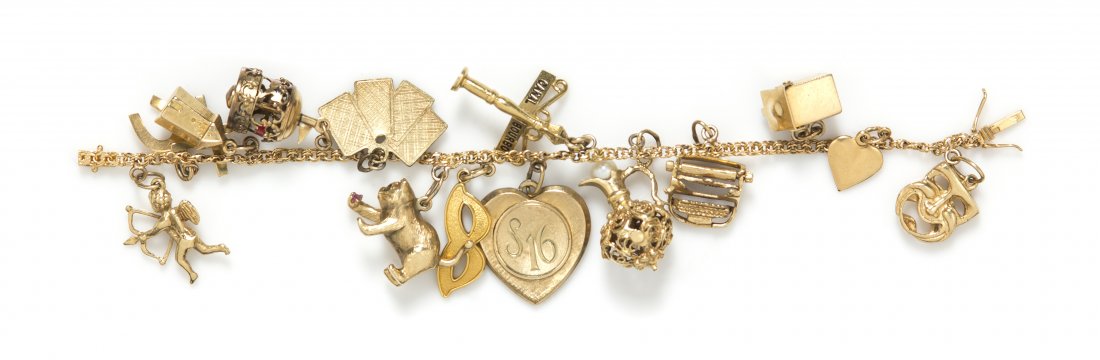 An 18 Karat Yellow Gold Charm Bracelet with 14 Attached: An 18 Karat Yellow Gold Charm Bracelet with 14 Attached Charms, including gold and gold tone charms in various designs including a jack-in-the-box, a typewriter, Cupid, a carousel and a windmill. Brac