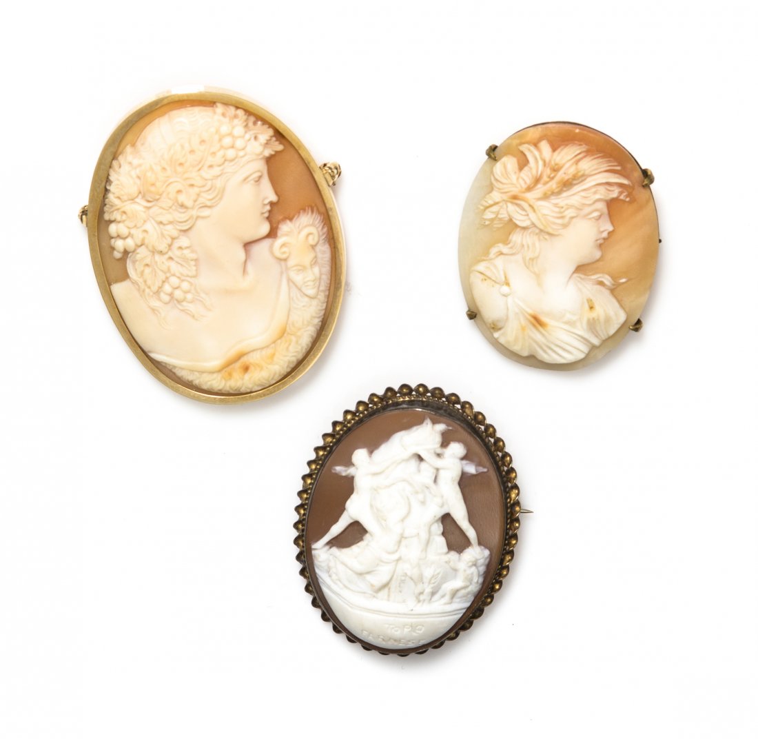 A Collection of Cameo Brooches,: A Collection of Cameo Brooches, consisting of three shell cameos, the largest depicting a Classical male profile, possibly Dionysus, within a 14 karat yellow gold bezel setting, together with two came