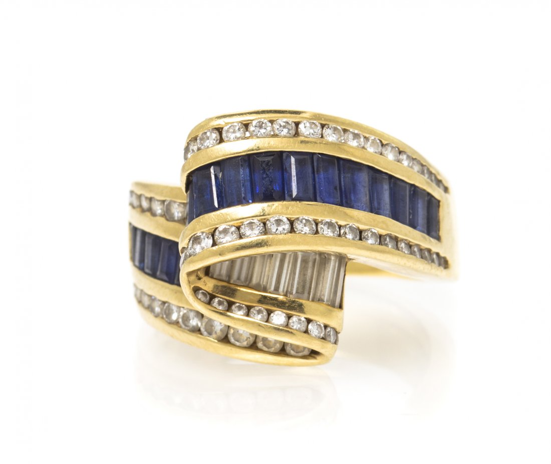 An 18 Karat Yellow Gold, Diamond and Sapphire Ring, Cha: An 18 Karat Yellow Gold, Diamond and Sapphire Ring, Charles Krypell, in a ribbon design, containing numerous round brilliant cut diamonds weighing 0.68 carat total, seven baguette cut diamonds weighin