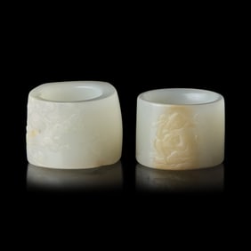 Two Chinese Carved Russet and White Jade Archer's Rings 清 白玉帶沁