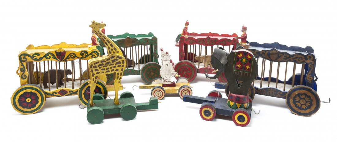 An American Painted Wood Travelling Circus Set, Height: An American Painted Wood Travelling Circus Set, comprising four caged train cars and three open train carts with an elephant, a giraffe and a clown. Height of tallest 13 inches. Property from the Coll