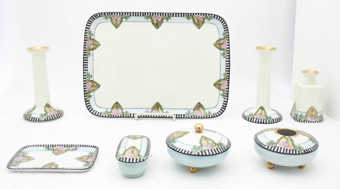 A Limoges Eight Piece Dresser Set Length of tray 12 3/4: A Limoges Eight Piece Dresser Set comprising two tall bottles, a lidded box with tray, a short rectangular shaped bottle, two round lidded vessels, and a tray, all decorated with a geometric and flora