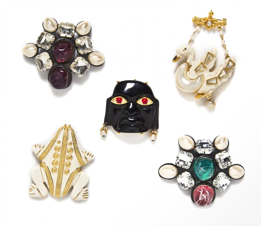 A Group of Five Kenneth Jay Lane Brooches,: A Group of Five Kenneth Jay Lane Brooches, comprised of a goldtone and cream enamel frog brooch, a cream enamel, rhinestone and faux pearl swan brooch, a faux carved onyx and rhinestone Tiki head broo