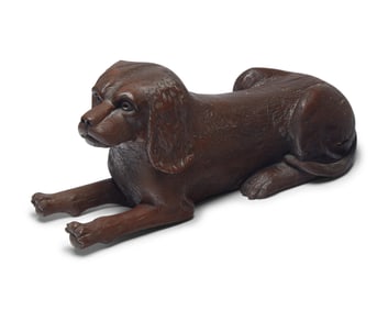 A Carved and Brown- Painted Figure of a Reclining Spaniel
