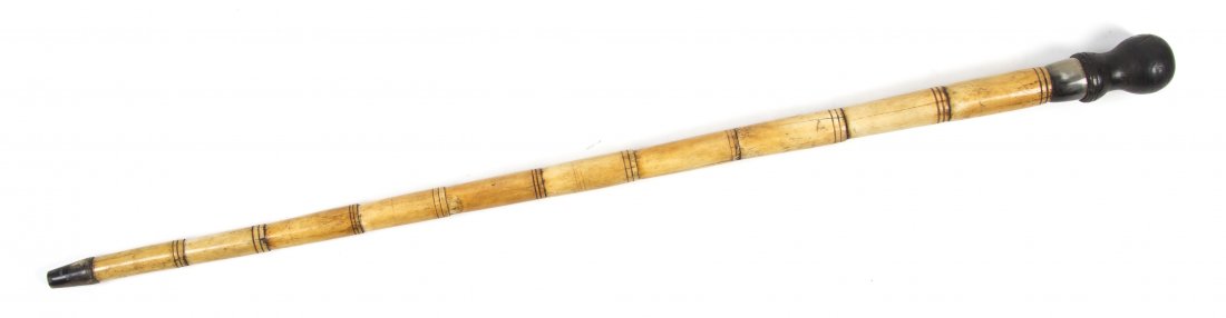 A Continental Ebonized Wood, Horn and Bone Walking Stic: A Continental Ebonized Wood, Horn and Bone Walking Stick, having a turned knob handle over the segmented tapering shaft, ending in a horn ferrule. Length 33 7/8 inches.