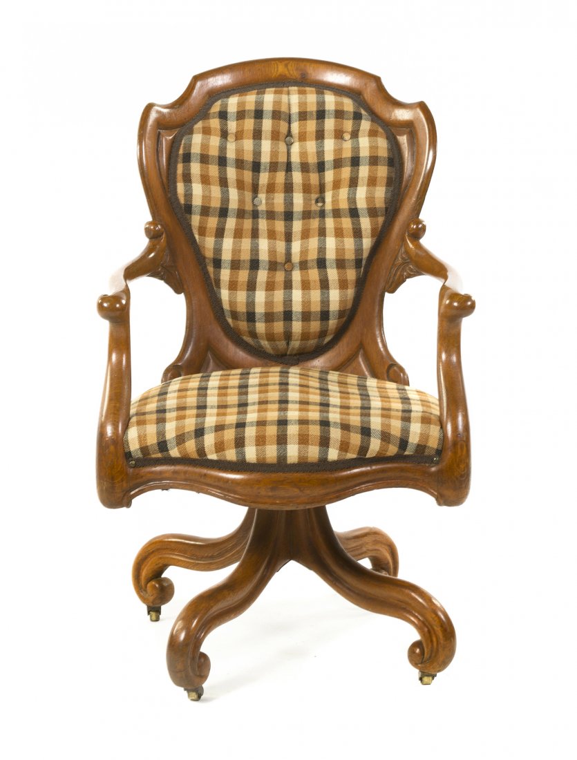 An American Oak Desk Chair, Belter, Height 37 inches.: An American Oak Desk Chair, Belter, the shield form back with button tufted upholstery over the scrolled arms above the upholstered seat, raised on a quadripartite base ending in casters. Height 37 in