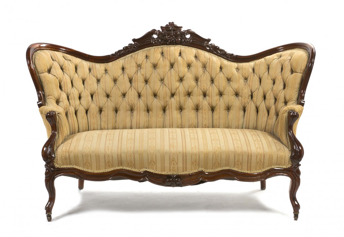 A Victorian Camel Back Settee, Height 42 x width 56 1/2: A Victorian Camel Back Settee, 19th century, having a foliate and grape carved crest rail over the button tufted upholstered back, raised on carved cabriole legs set on casters. Height 42 x width 56 1