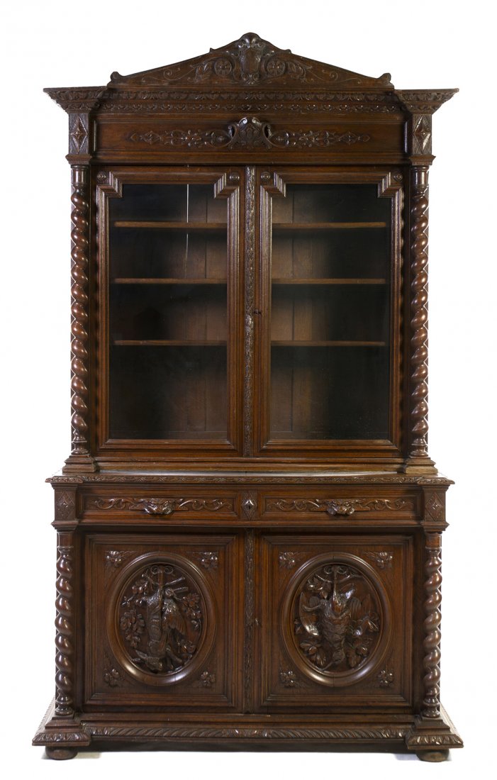 A Renaissance Revival Oak Hunt Cabinet, Height 102 x wi: A Renaissance Revival Oak Hunt Cabinet, the superstructure having a peaked crest with carved shield and foliate decoration over the molded cornice and conforming decorated frieze above two glazed door