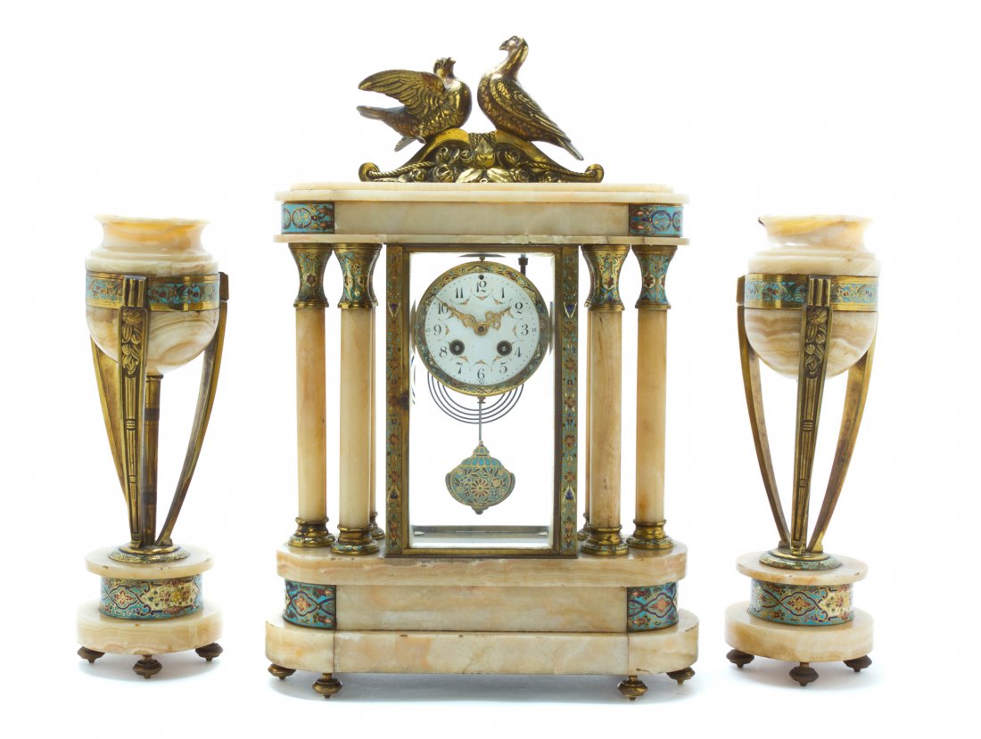 A French Champleve, Onyx and Gilt Metal Mounted Clock G: A French Champleve, Onyx and Gilt Metal Mounted Clock Garniture, comprising a clock and two urns, the clock surmounted by two doves, over the circular dial with Arabic hours, marked France, flanked by