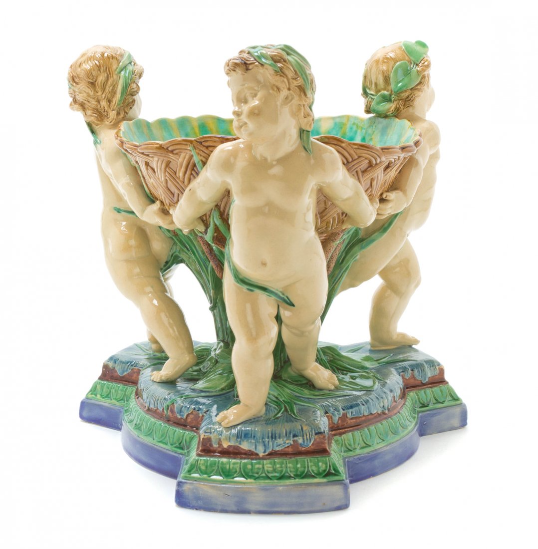 A Minton Majolica Center Piece, Height 11 1/4 inches.: A Minton Majolica Center Piece, modeled as three putti supporting a woven basket, over the tripartite base. Height 11 1/4 inches.